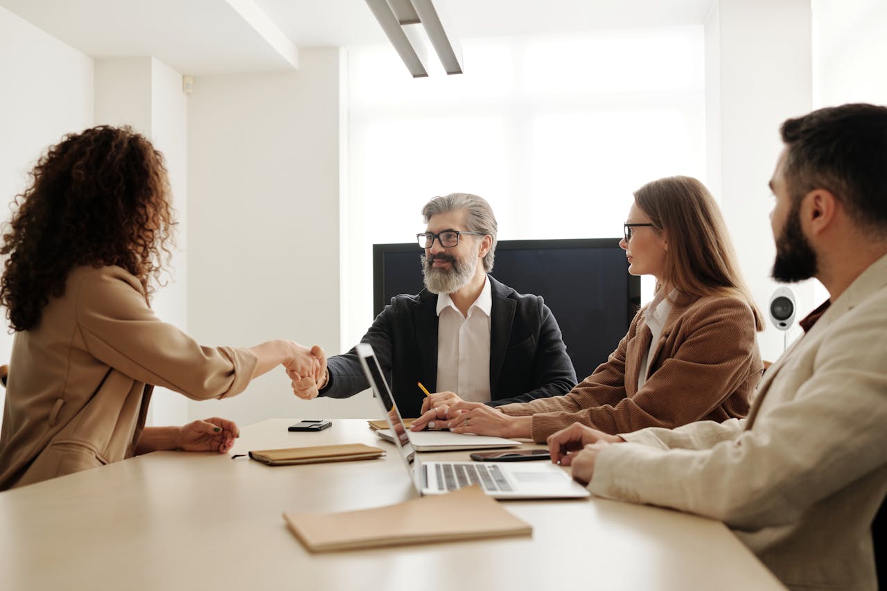 Offerings Colleagues in an office celebrating a successful negotiation with a handshake.